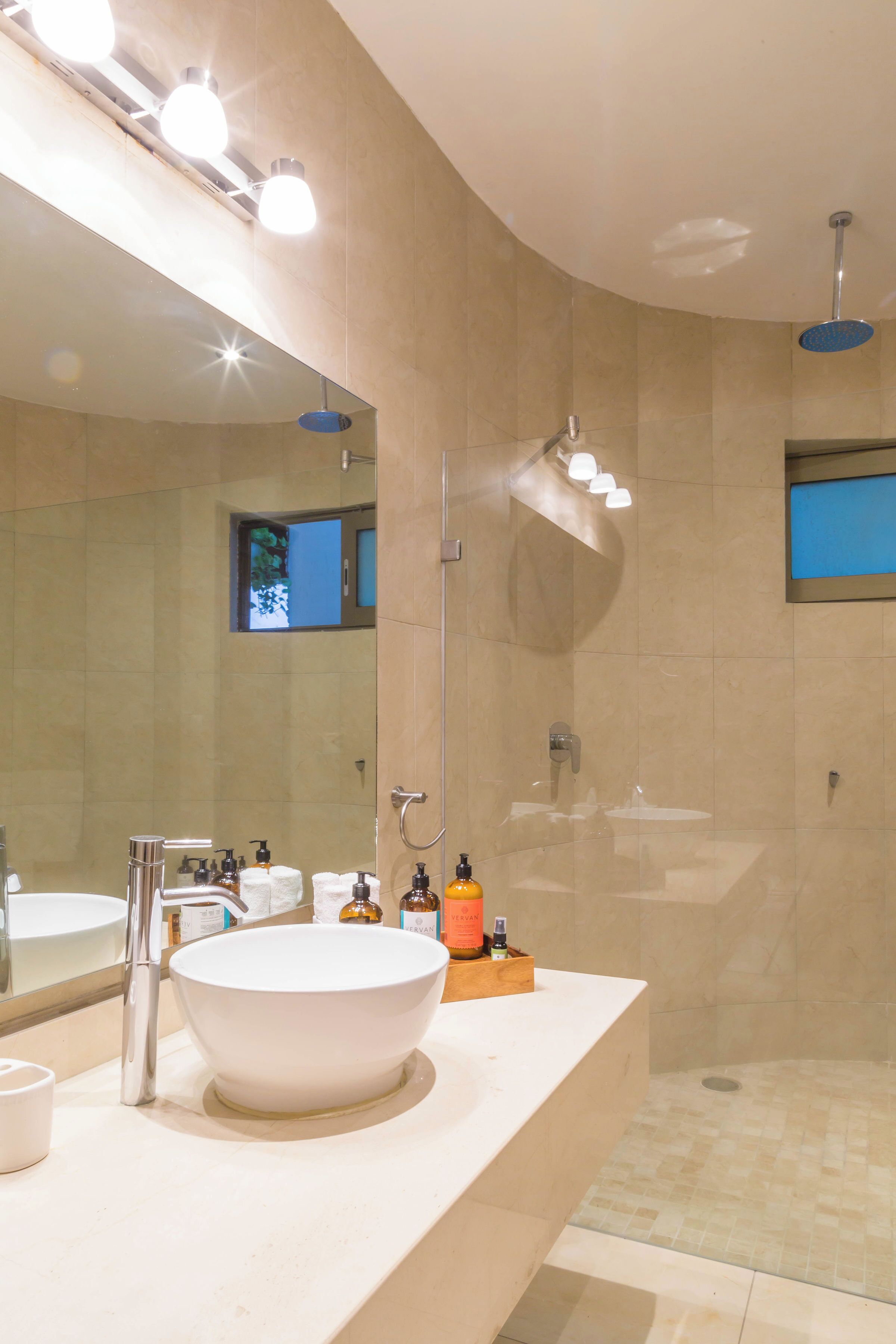 Un baño moderno con un espejo grande, un lavabo blanco y una zona de ducha.