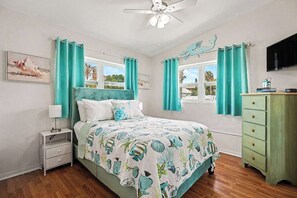 Ein Schlafzimmer mit einem Bett, einem Nachttisch, einer Kommode und einem Deckenventilator.