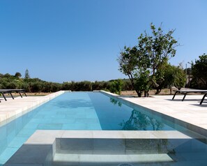 A rectangular swimming pool with clear blue water, surrounded by a tiled deck. - Citrus Grove (Rethymno)