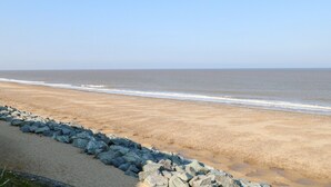 A beach with a rocky shoreline and a clear sky. - California Summers (Great Yarmouth)