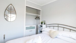 A neatly made bed with white linens, a heart-shaped pillow, and a rolled towel. - California Summers (Great Yarmouth)