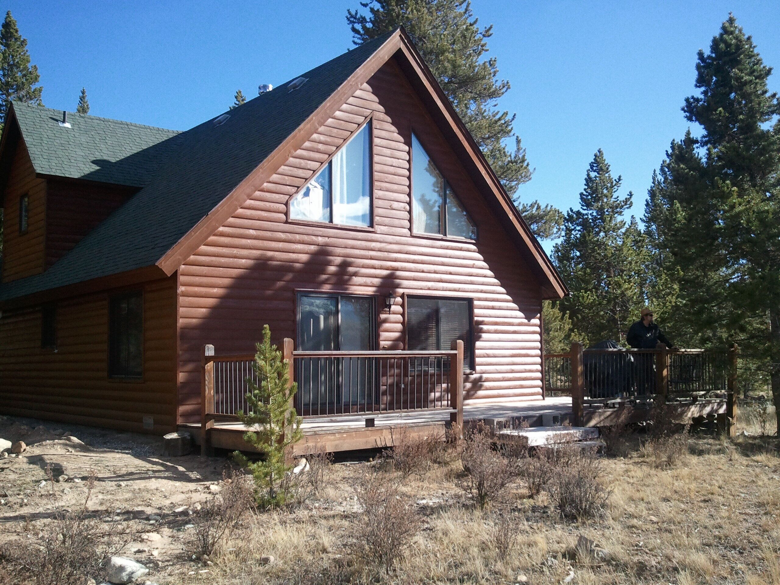 A log cabin with a large front porch, a second-story balcony, and a chimney.
