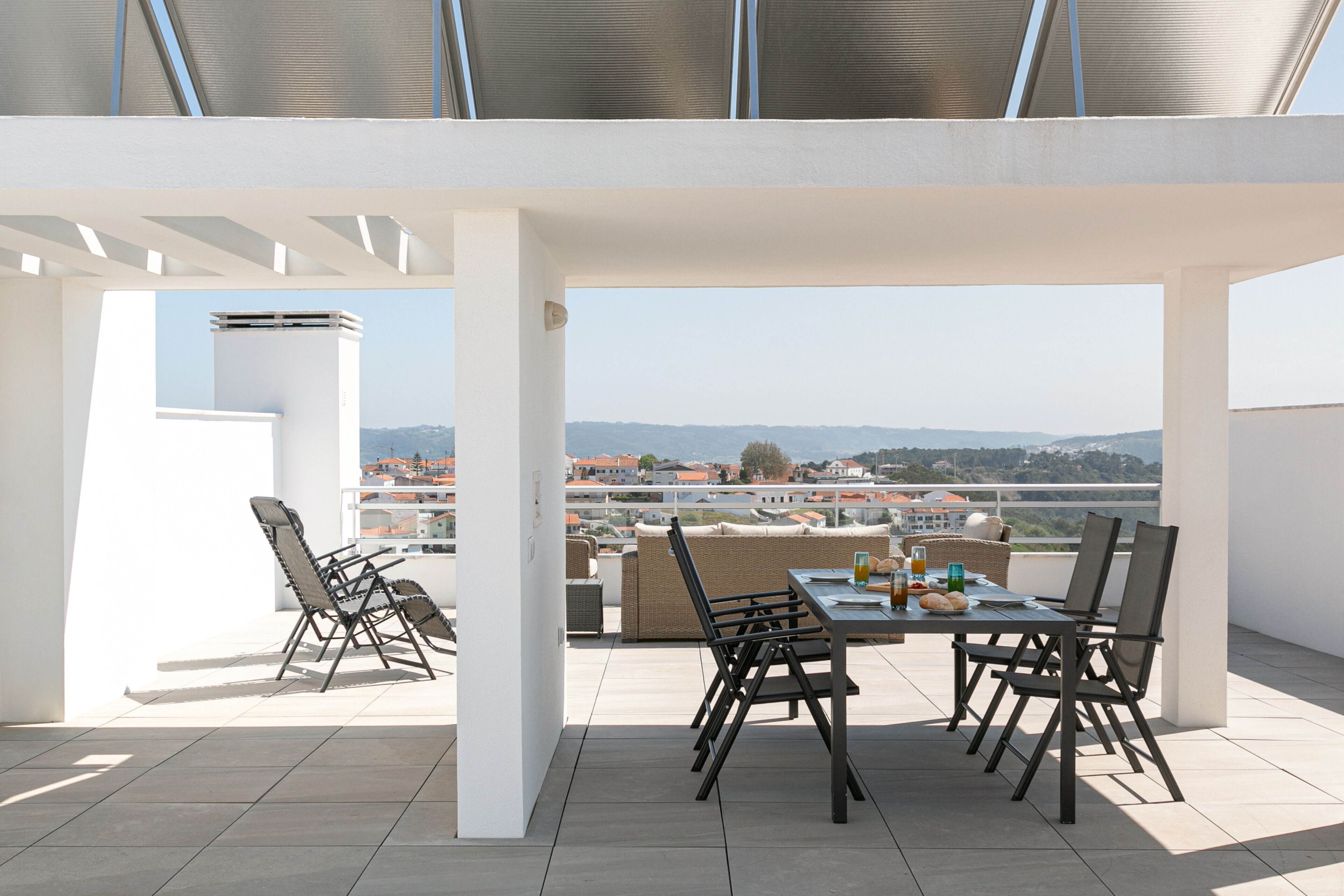 A rooftop terrace with a dining table, chairs, and a view of the cityscape.