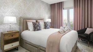 A hotel room with a large bed, a nightstand, a sofa, and a view of the city. - Casa Urlaub - Panoramic Rooftop View (Nazaré)