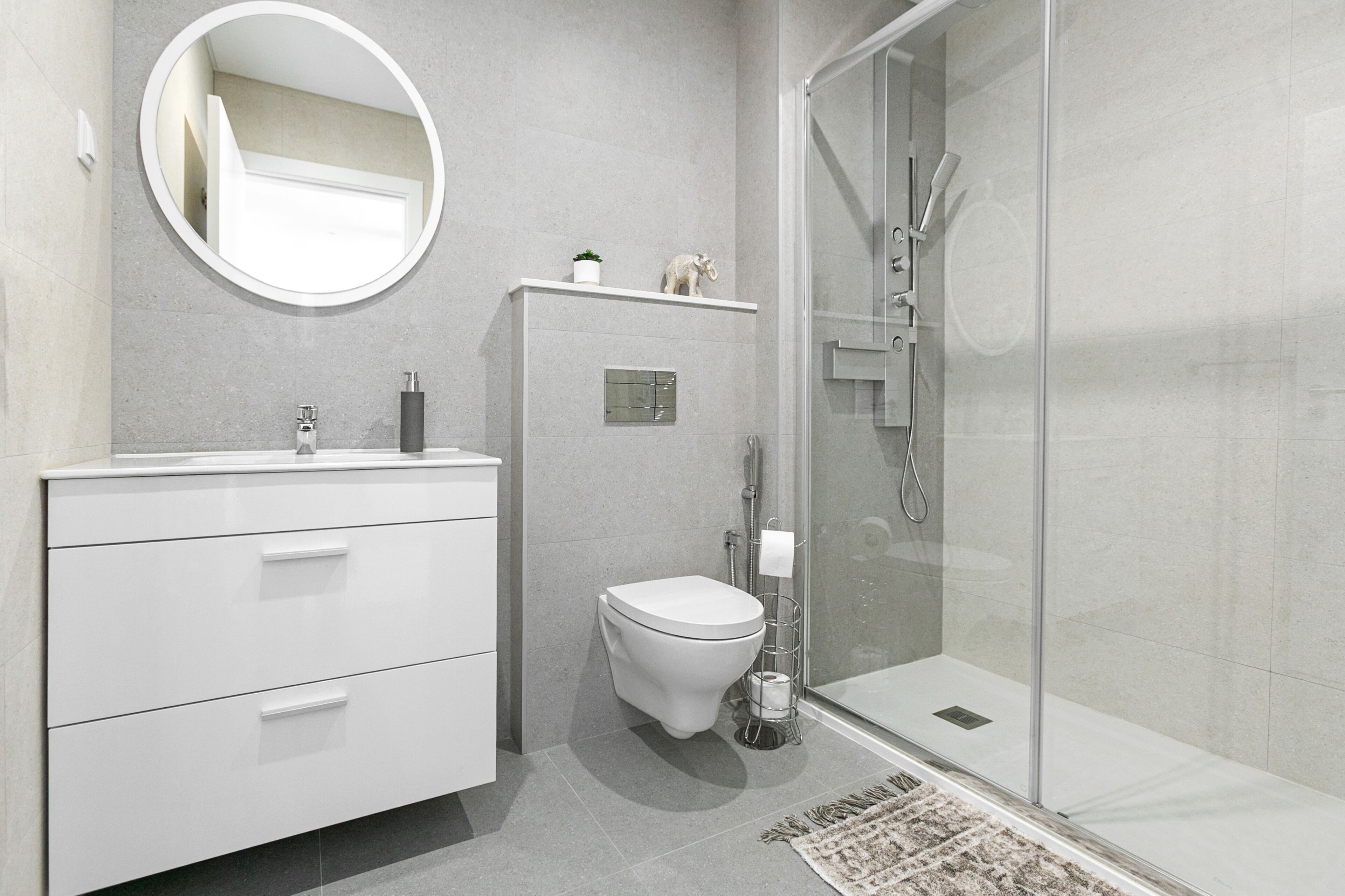 A modern bathroom with a white vanity, a toilet, and a glass-enclosed shower.