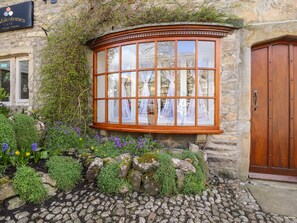 A stone building with a large bay window, a wooden door, and a sign for 'The Blestones Café'. - 2 The Square (Skipton)