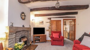 A cozy living room with a stone fireplace, a red armchair, and a red sofa. - 2 The Square (Skipton)