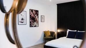 A modern bedroom with a bed, a chair, and three framed pictures on the wall. - Gorgeous Apartment in old City Centre of Antwerp 1 (Antwerp)