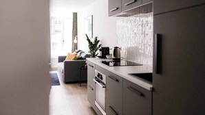 A modern kitchen with grey cabinets, a black countertop, and a stainless steel kettle. - Gorgeous Apartment in old City Centre of Antwerp 1 (Antwerp)