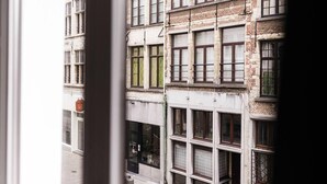 A multi-story building with a mix of brick and plaster facades, large windows, and a visible fire hydrant on the ground floor. - Gorgeous Apartment in old City Centre of Antwerp 1 (Antwerp)