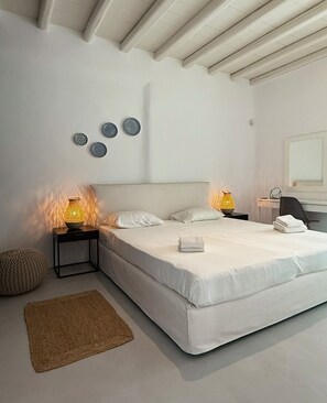 Une chambre à coucher avec un lit, deux tables de chevet avec des lampes, un tapis rond et des éléments de décoration murale.