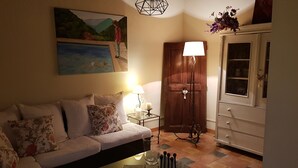 A living room with a sofa, a glass coffee table, a painting, a lamp, and a cabinet. - The villa (Beauvoisin)