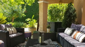An outdoor seating area with wicker furniture and potted plants. - The villa (Beauvoisin)