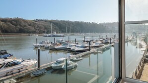 A marina with various boats docked, a clear sky, and a forested hillside in the background. - 33 Dart Marina (Dartmouth)