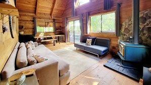 A cozy cabin interior with a sofa, a bench, a table, and a stone wall. - Romantic Off-Grid Cabin (Lytton)