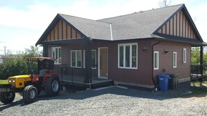 Ein zweistöckiges Haus mit Veranda, Garage und Auffahrt mit Kies.