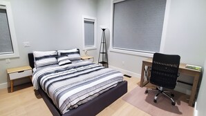 Ein Schlafzimmer mit einem Bett, Nachttischen, einem Schreibtisch und einem Stuhl.