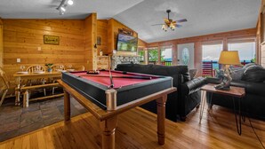 Ein Holzinterieur mit Billardtisch, einer Couch und einem Essbereich.