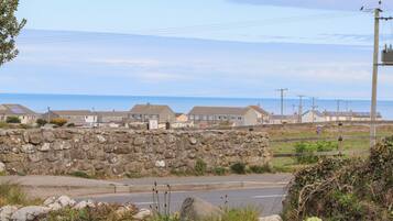 A coastal road with stone walls and houses in the background.