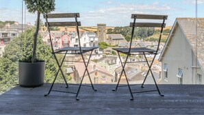 Dos sillas plegables en un balcón con vistas a un pueblo con edificios históricos y una torre de iglesia.