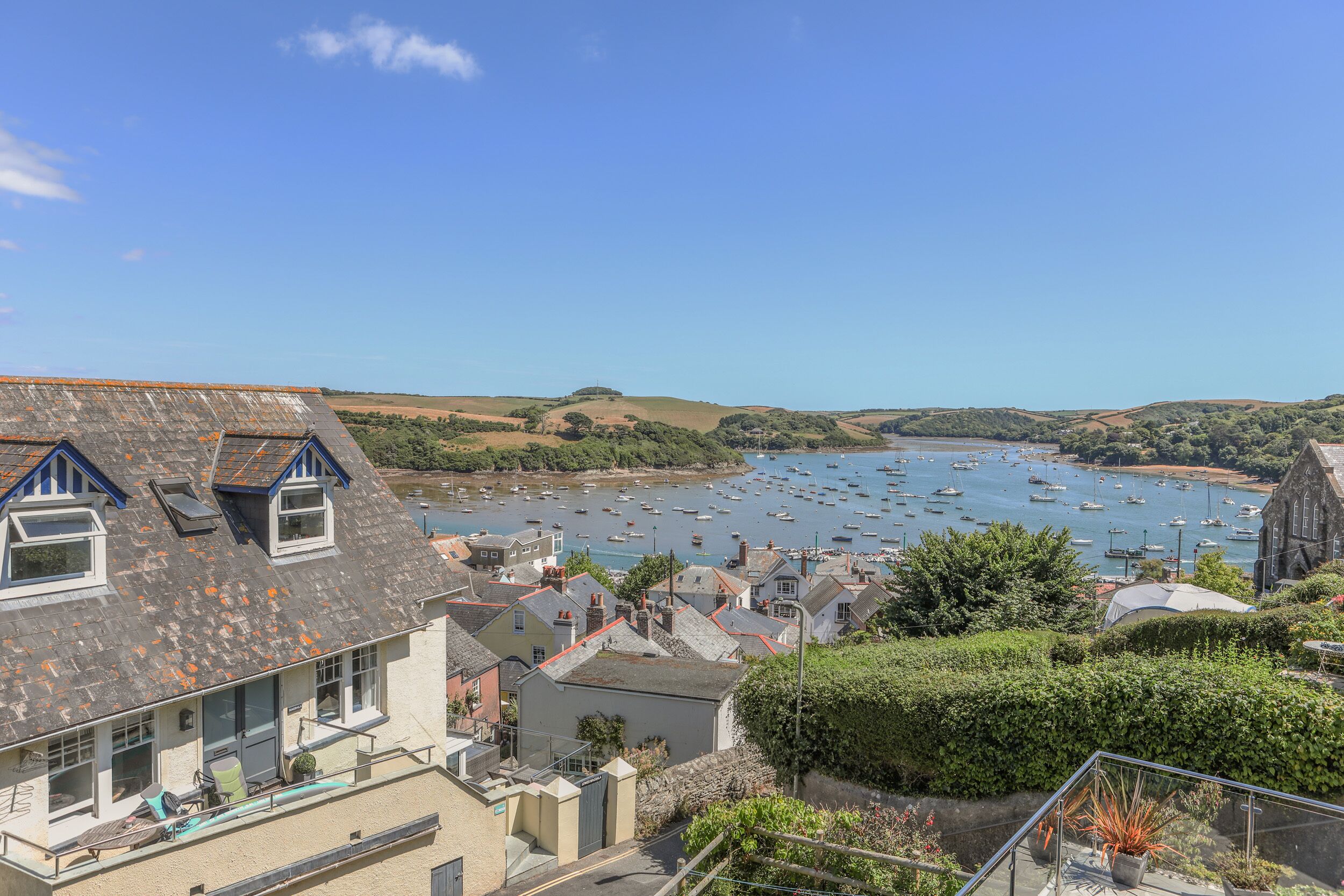 A coastal town with a harbor filled with boats, houses with sloped roofs, and a clear blue sky.