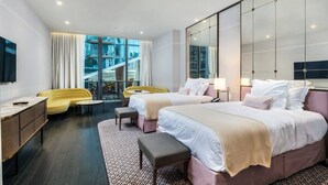 A modern hotel room with two beds, a sofa, a desk, and a large window with a view of a building. - Suite 212 located in SLS Lux Brickell by City Escapes (Miami)