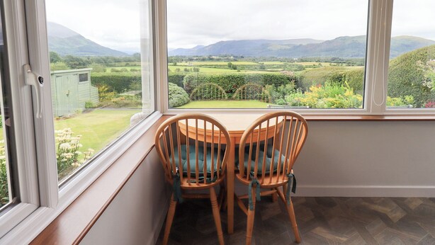 Una habitación con vistas a un paisaje verde, dos sillas de madera y una ventana con techo de madera.