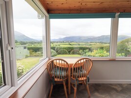 Una habitación con vistas a un paisaje verde, dos sillas de madera y una ventana con techo de madera.