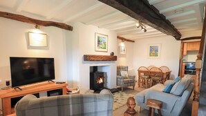 Un salón acogedor con chimenea, televisor y comedor con muebles de madera.