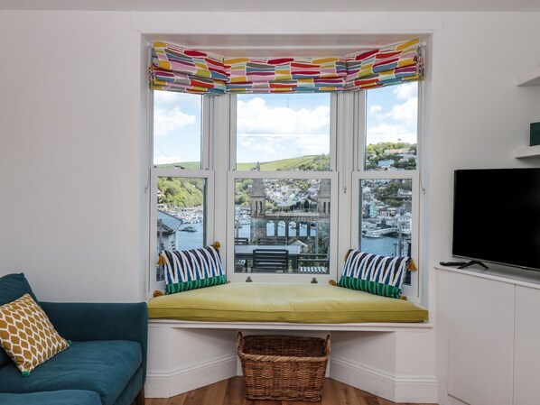 A bay window with a colorful striped valance, a green cushioned bench, and a wicker basket.