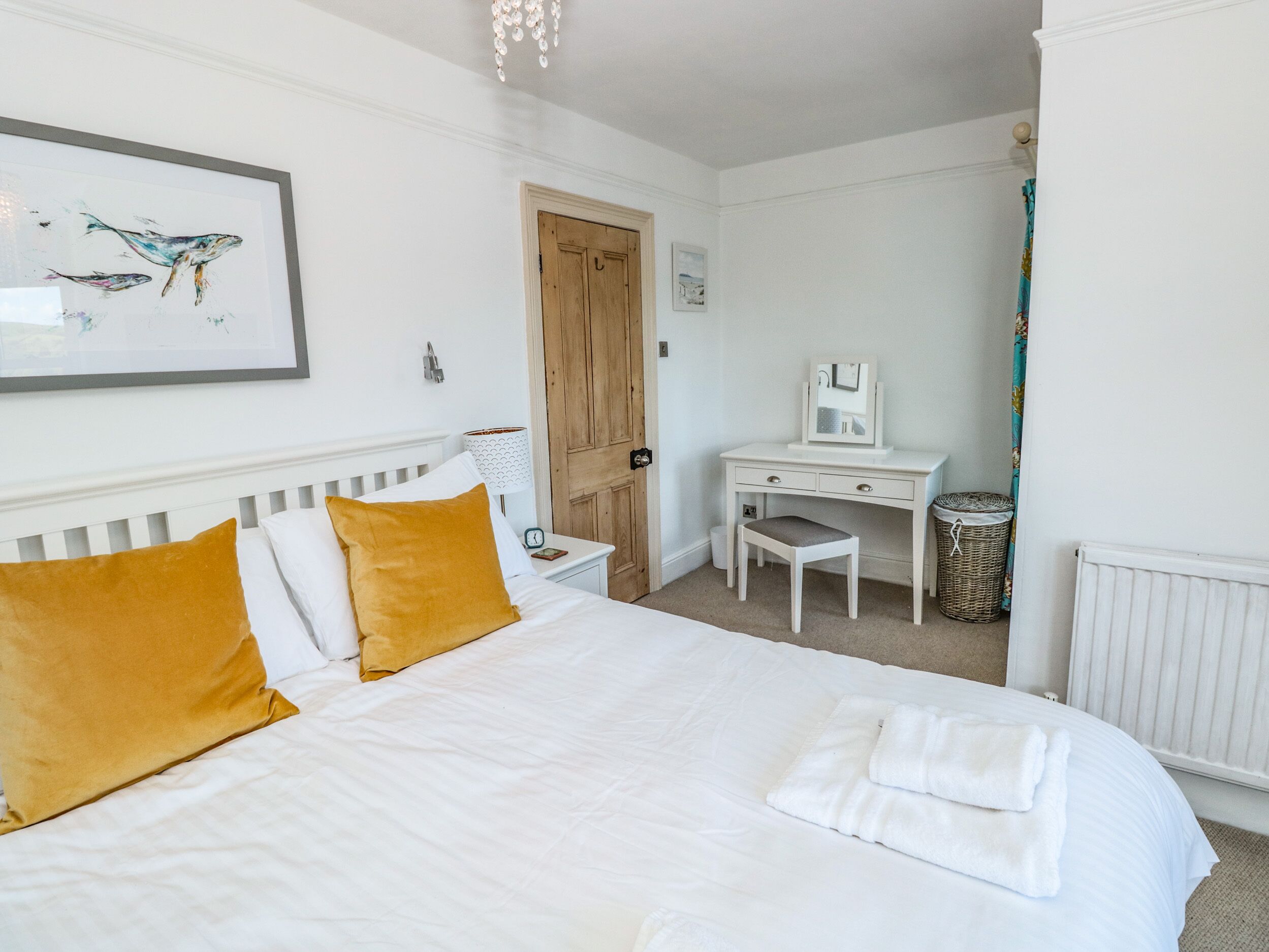 A bedroom with a bed, a desk, a chair, a radiator, and a door.