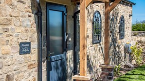 A stone building with a black door, wooden beams, and a sign reading "Woodland View". - Woodland View (Richmond)