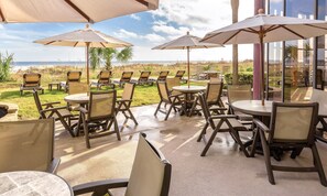An outdoor patio with tables and chairs, umbrellas, and a view of the beach. - 4th of July '23! Peaceful Beachfront, balcony, easy access to the beach. ENJOY (North Myrtle Beach)