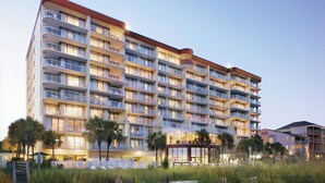 Et hotel med flere etager, altaner, poolområde og udsigt til stranden.