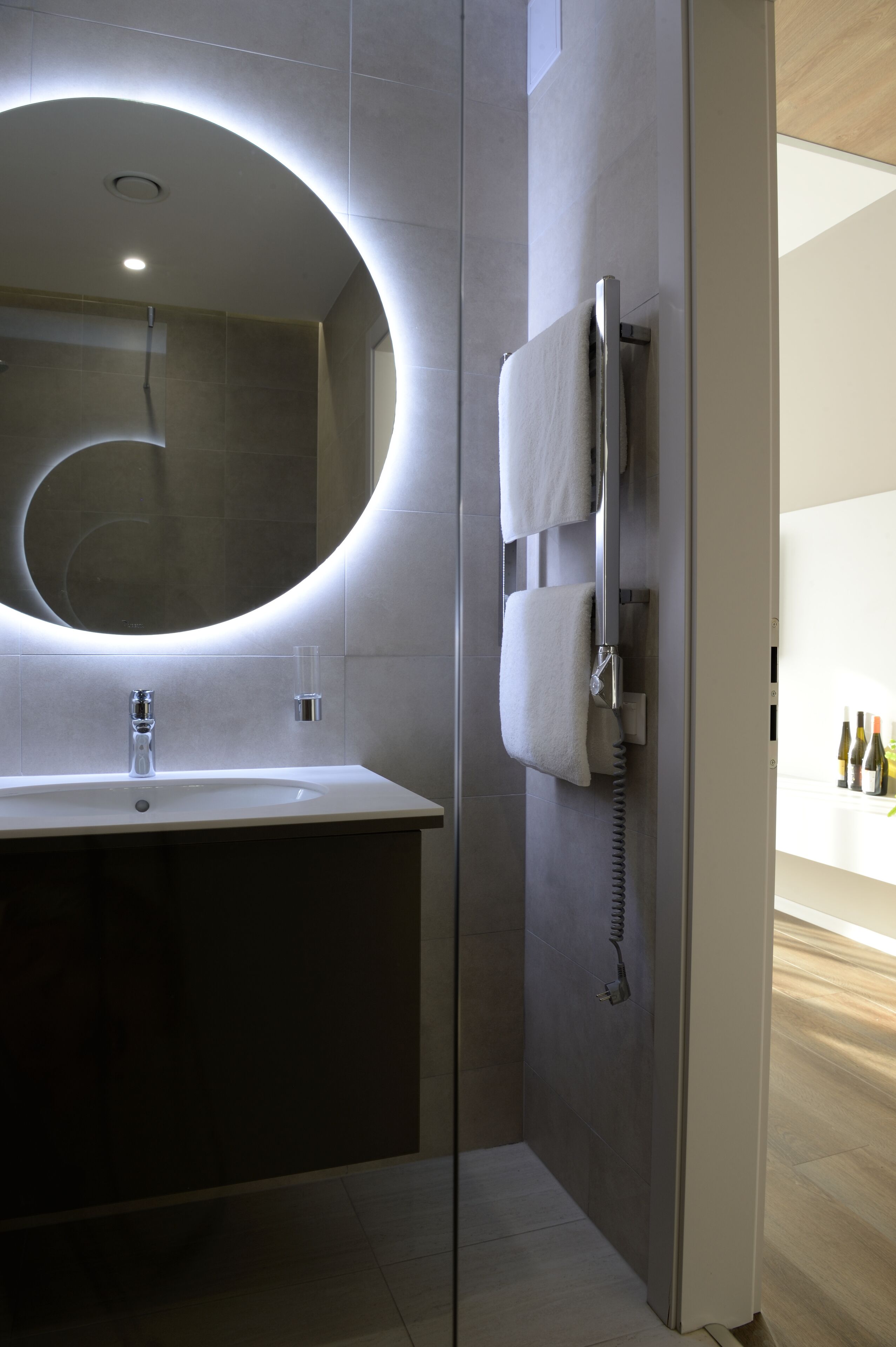 Un baño moderno con un espejo grande, un lavamanos y un perchero para toallas.