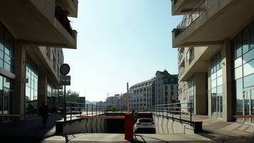 Una passerella pedonale con l'imbocco di un tunnel stradale, edifici moderni e cielo sereno.