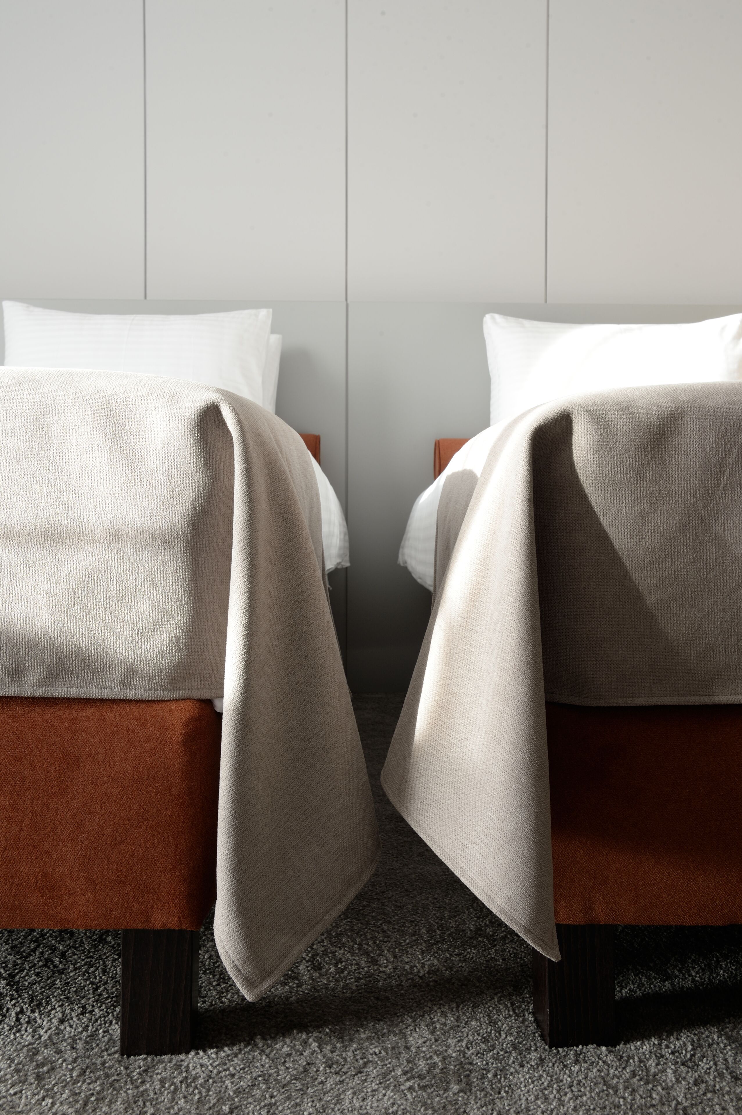 Ein Hotelzimmer mit zwei Betten, jeweils mit brauner Kopfteil und weißer Decke.