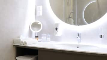 Un baño moderno con un espejo redondo, un lavabo y un inodoro.