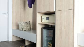 Een moderne kamer met een houten garderobe, een hangende kledingstuk, een klein plankje met een tas, en een vitrinekast met glazen deuren.