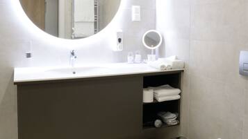 A modern bathroom with a round mirror, a sink, a toilet, and a towel rack.