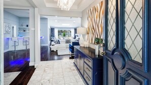 A modern living room with a dark wood floor, white sofas, a blue accent chair, and a large decorative mirror. - Modern Home with a Firepit, Heated Pool & Spa (Dallas)
