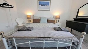 Ein ordentlich eingerichtetes Schlafzimmer mit Bett, Nachttischen, einem Sessel und einer Kommode.