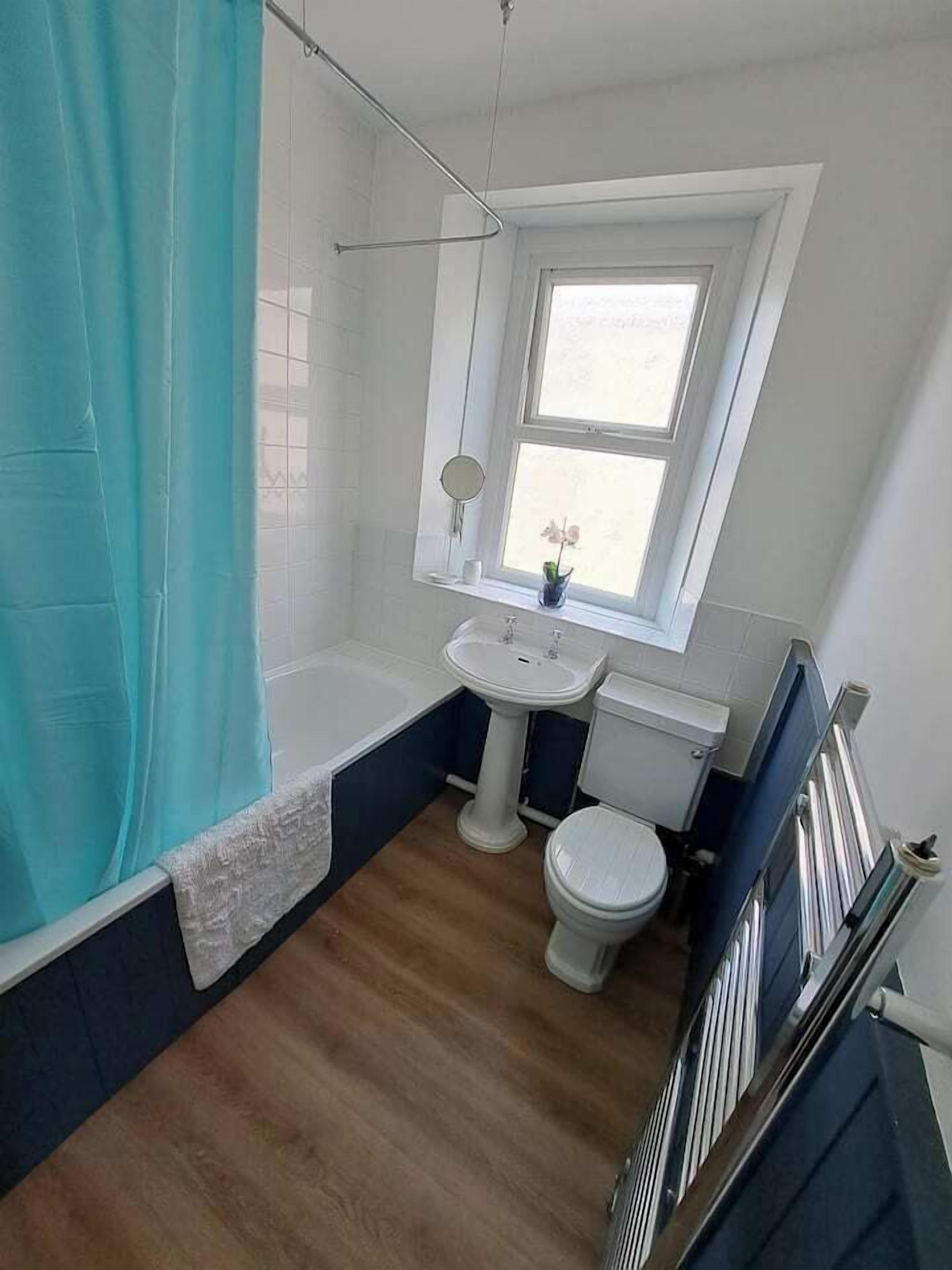 Ein Badezimmer mit Badewanne, Toilette, Waschbecken und einem Fenster.