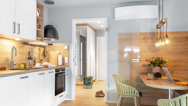 A modern kitchen with white cabinets, a wooden countertop, and a dining area with a table and chairs.