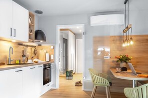 Cozinha moderna com armários brancos, bancada de madeira e área de jantar com mesa e cadeiras.