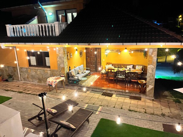 A house with a dining area, a sofa, and a poolside area.