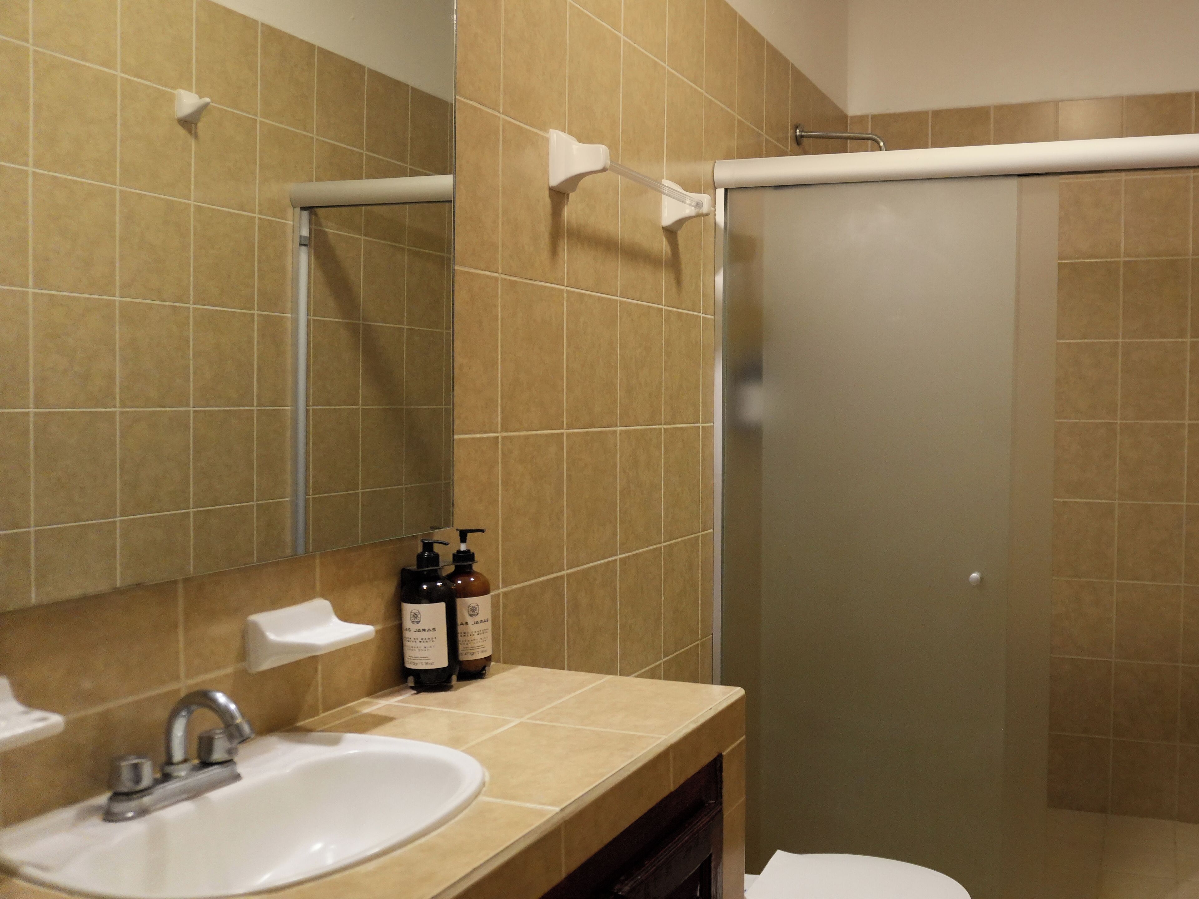 A bathroom with a sink, mirror, and toiletries.
