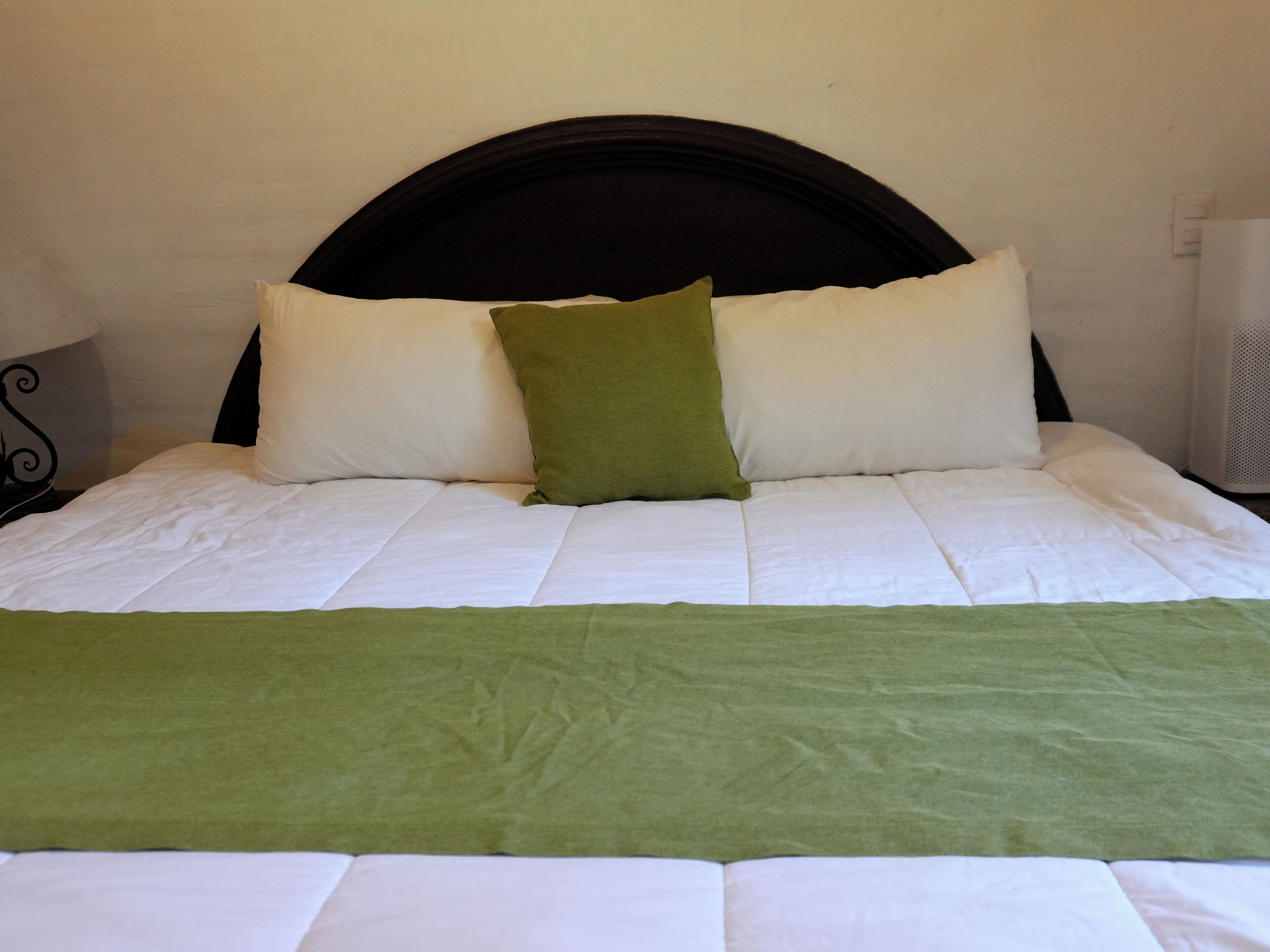 Un letto rifatto con biancheria bianca e una coperta verde.