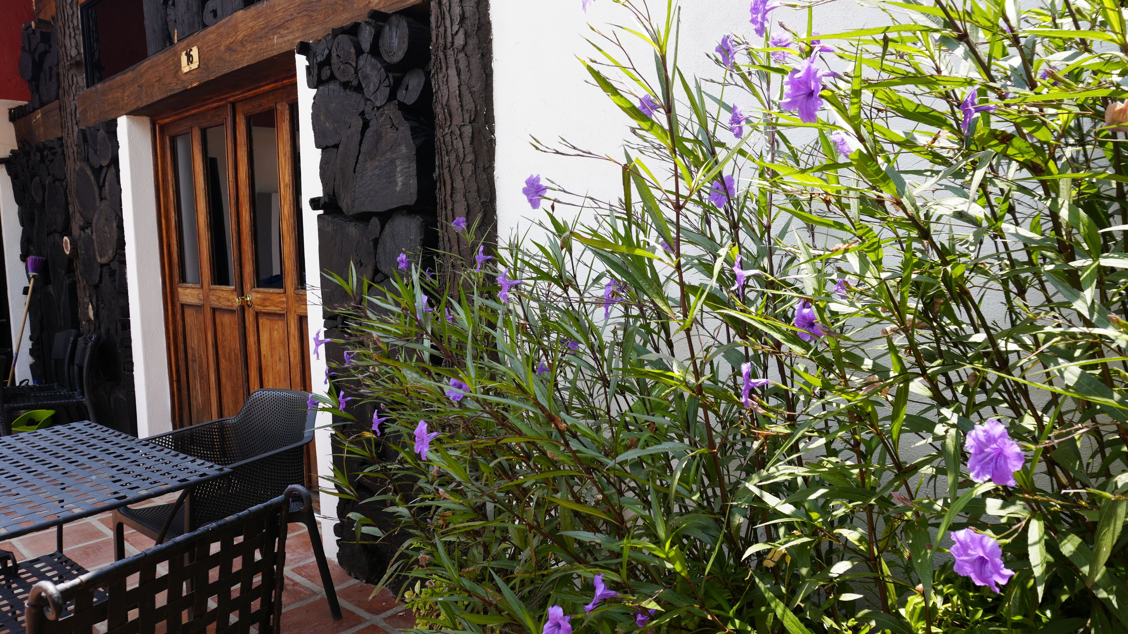 Un patio con una puerta de madera, una mesa de metal y una silla.