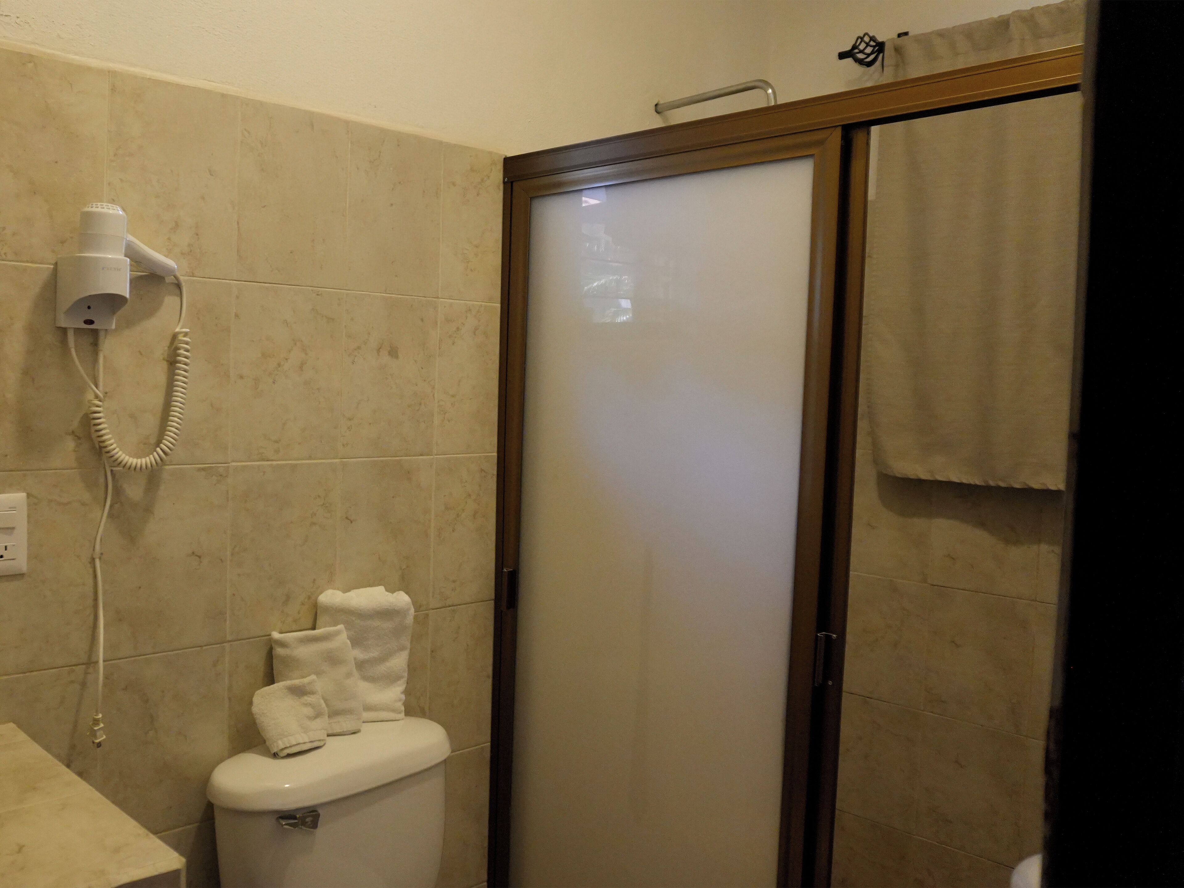 Un bagno con il water, un asciugacapelli e una cabina doccia.